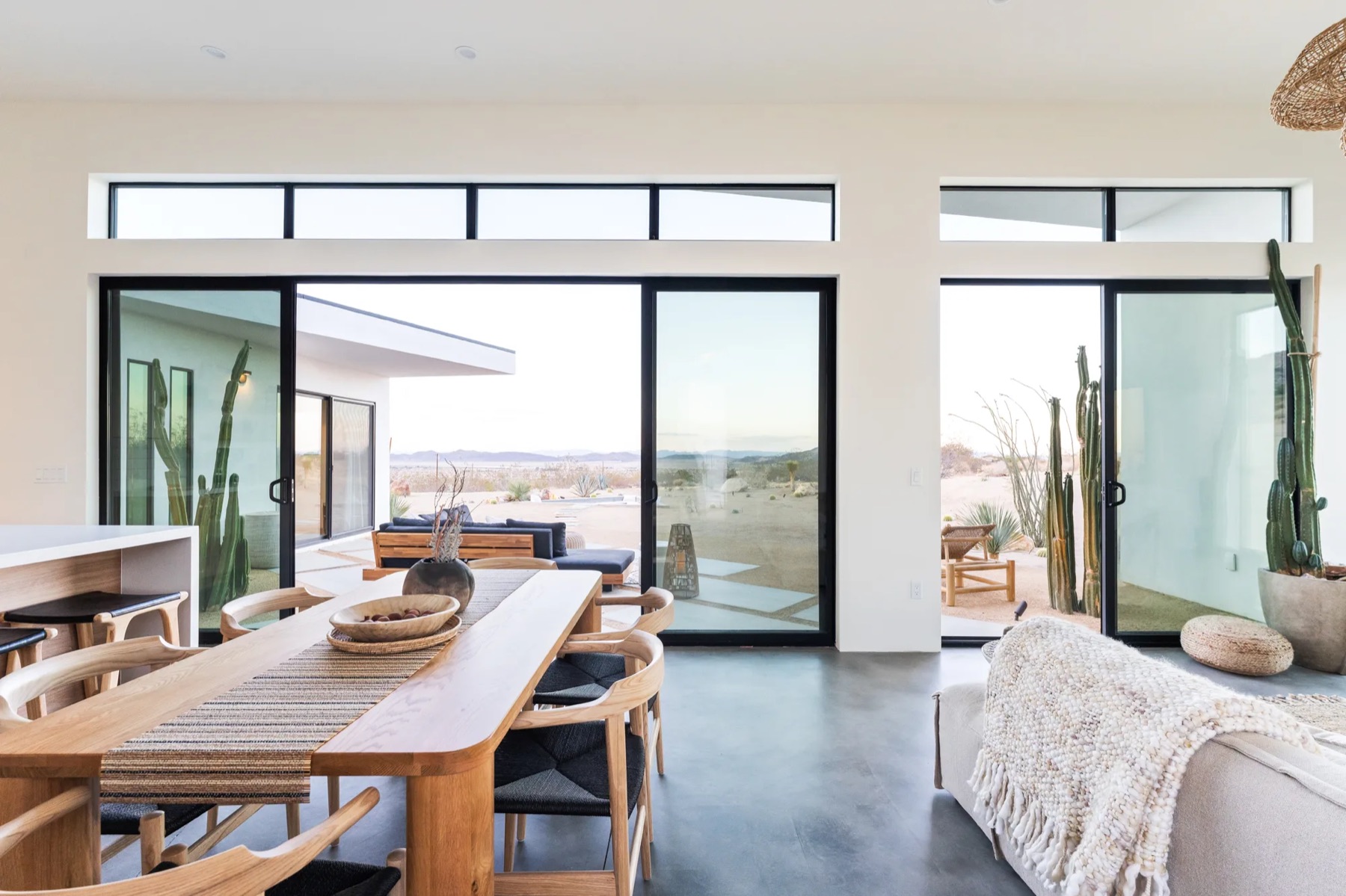Joshua Tree House dining room with a long timber table and glass walls opening to the desert